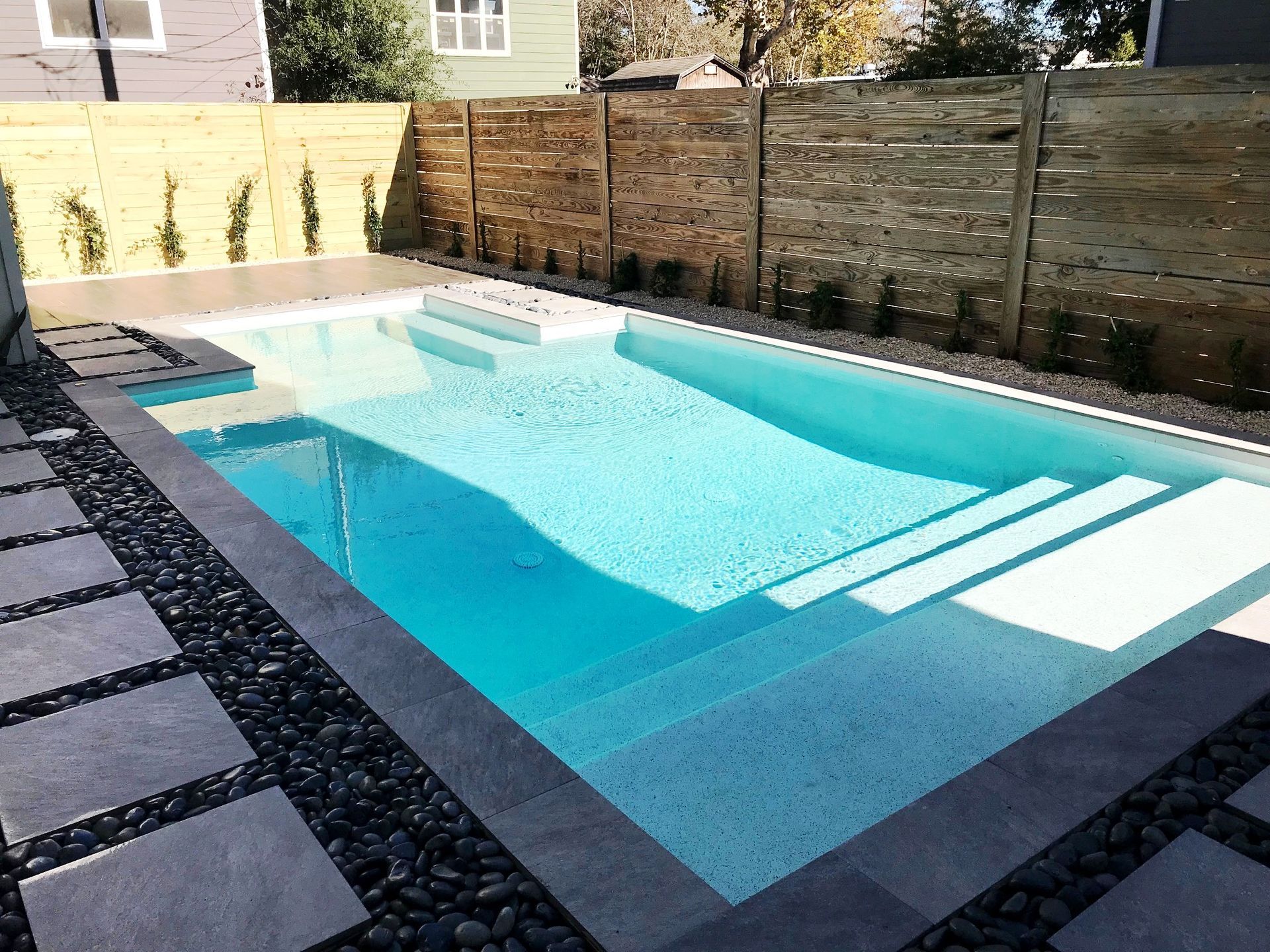 A large swimming pool with a wooden fence surrounding it