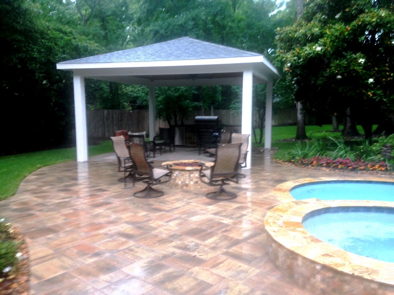 A patio with a fire pit and chairs next to a pool.