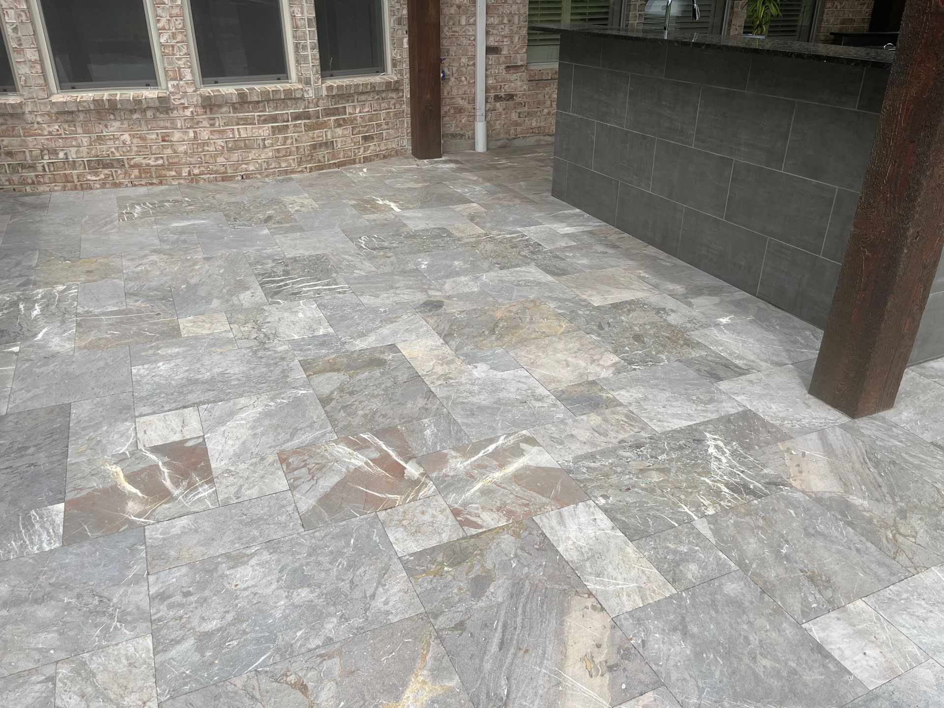 A patio with a tiled floor and a brick wall in the background.