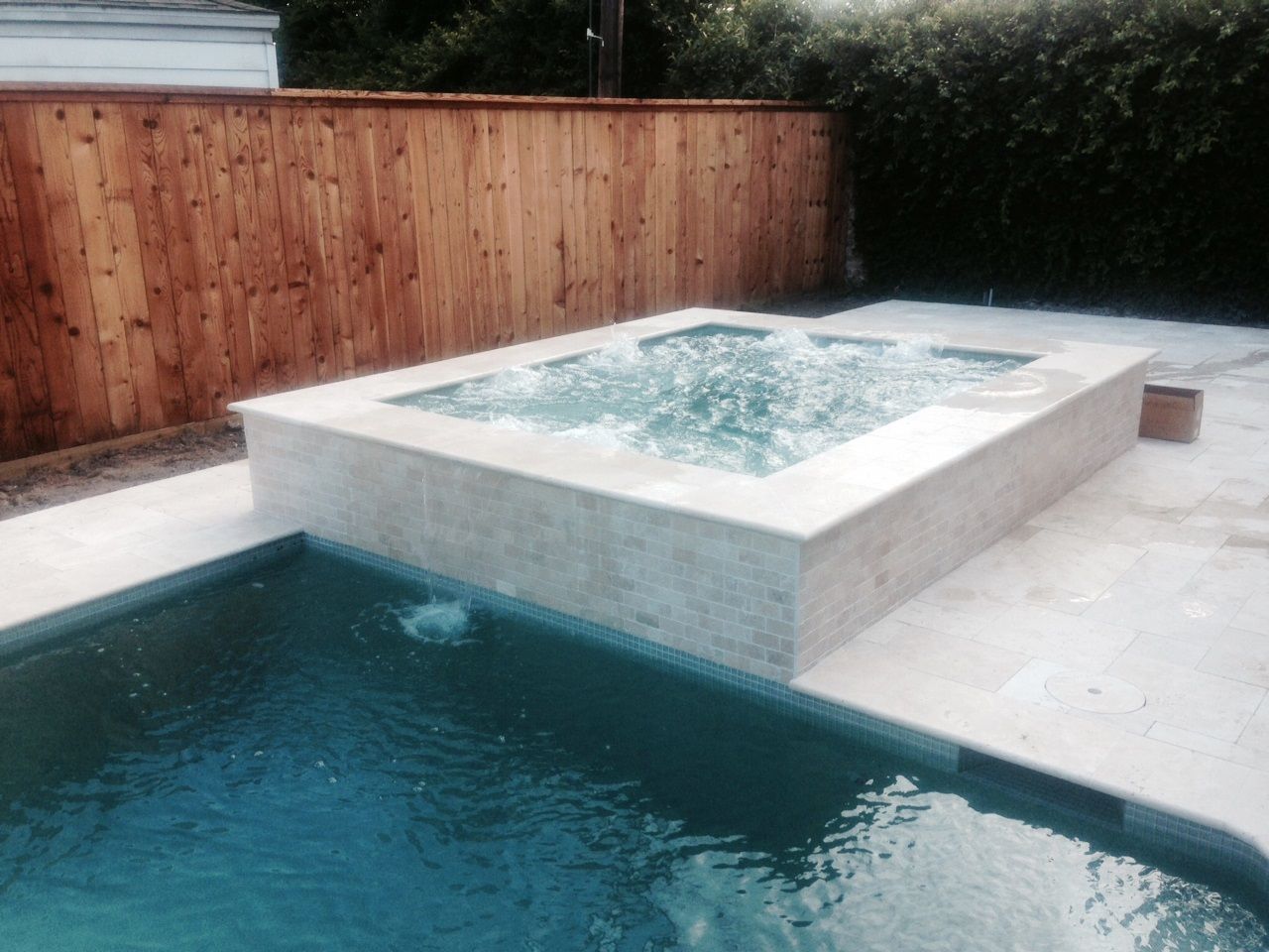 A large swimming pool with a hot tub in the middle of it.