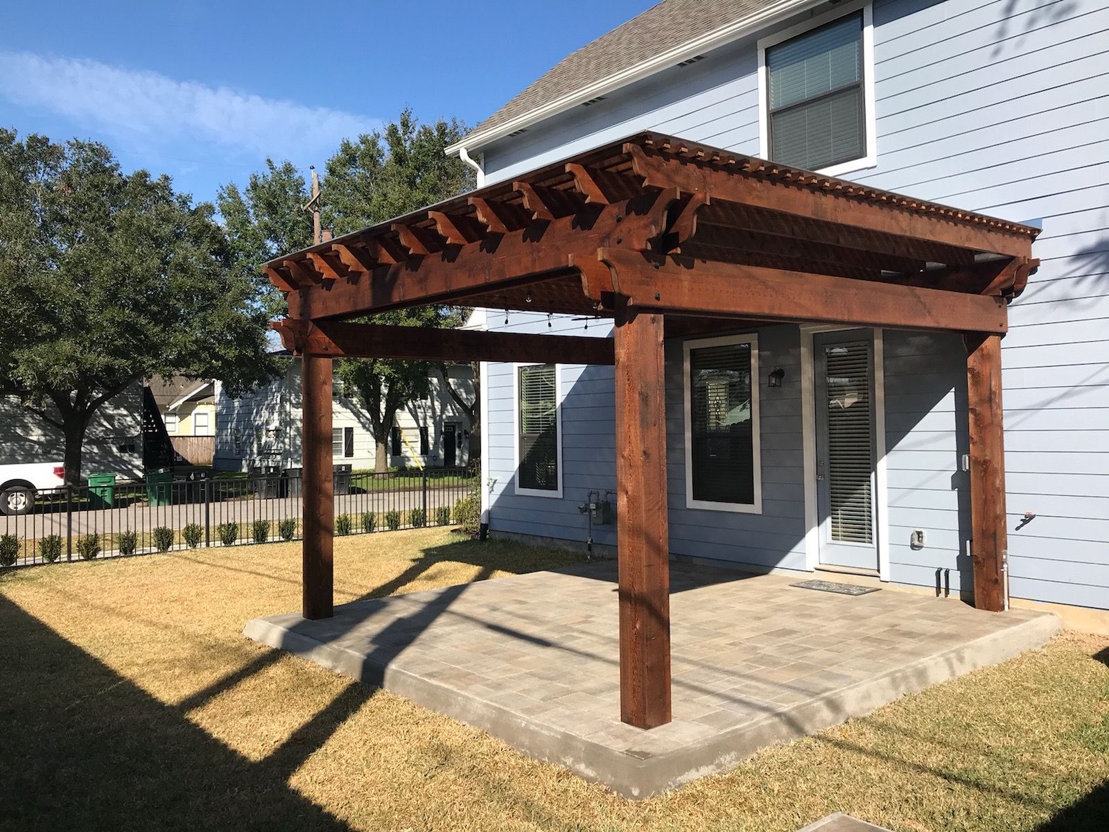 A blue house with a wooden pergola in front of it.