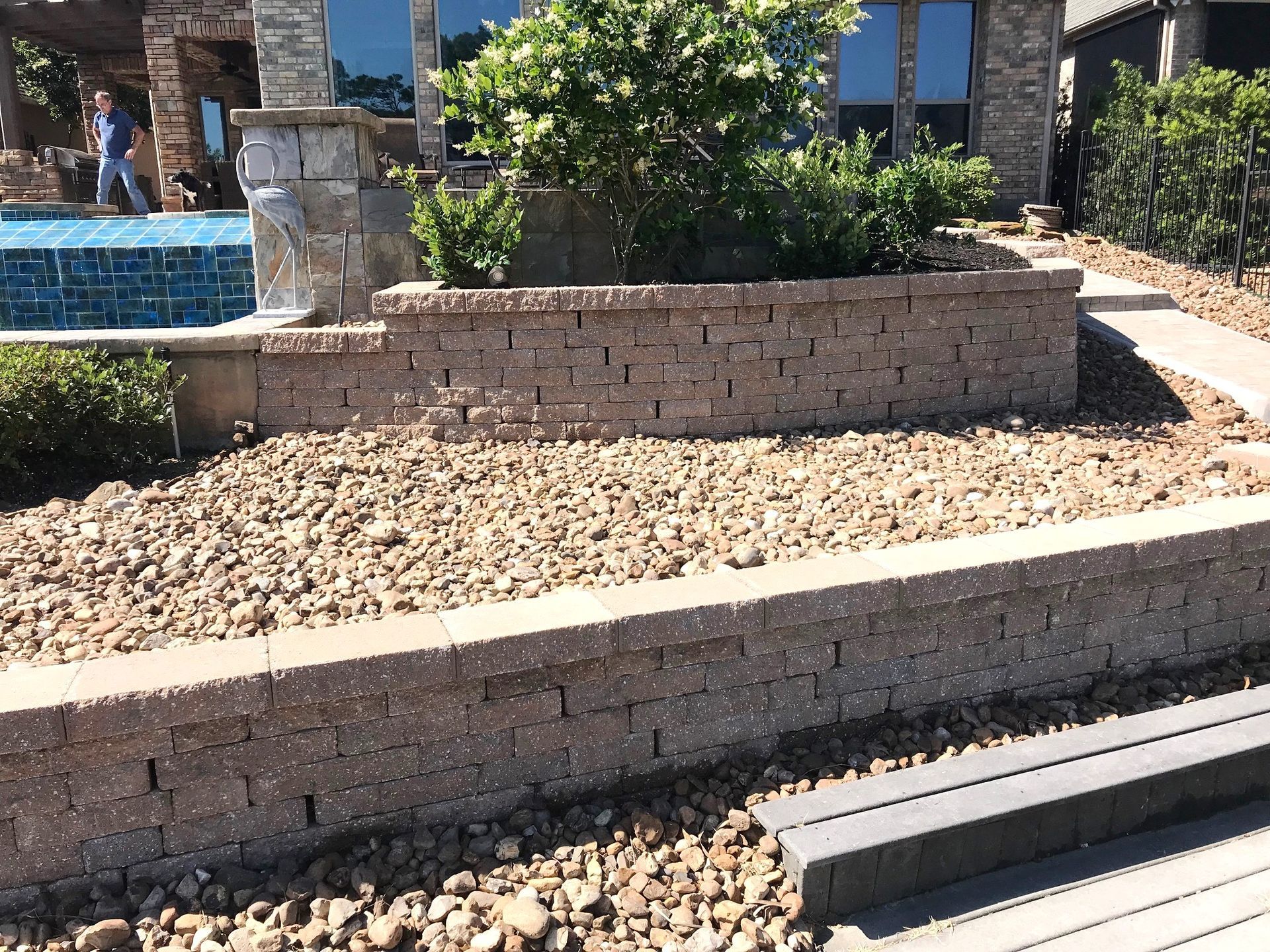 A brick wall in front of a house with a walkway leading to it