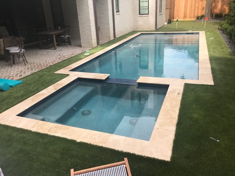 A large swimming pool is surrounded by a lush green lawn.