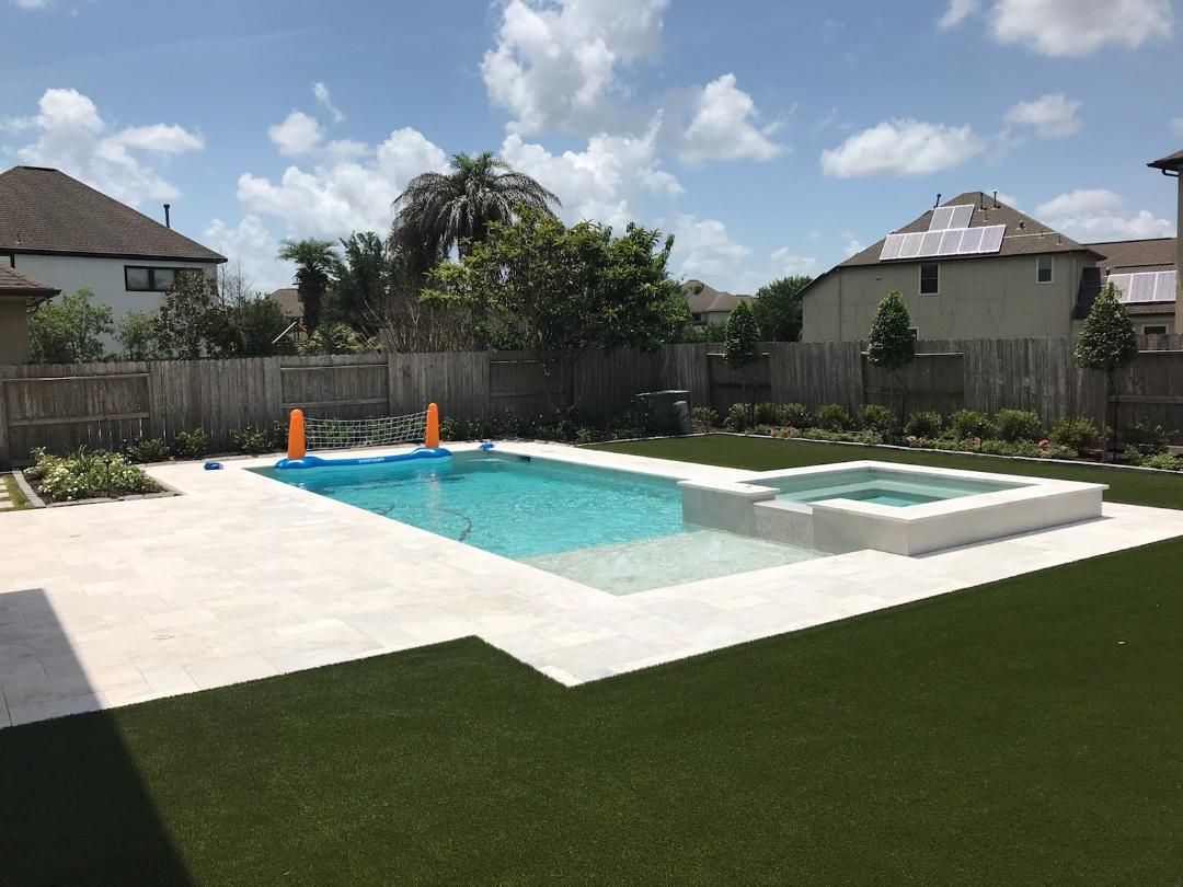 A large swimming pool with a hot tub in the backyard of a house.