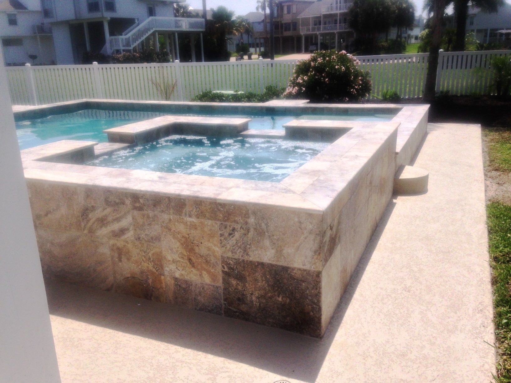 A large swimming pool with a hot tub in the backyard.
