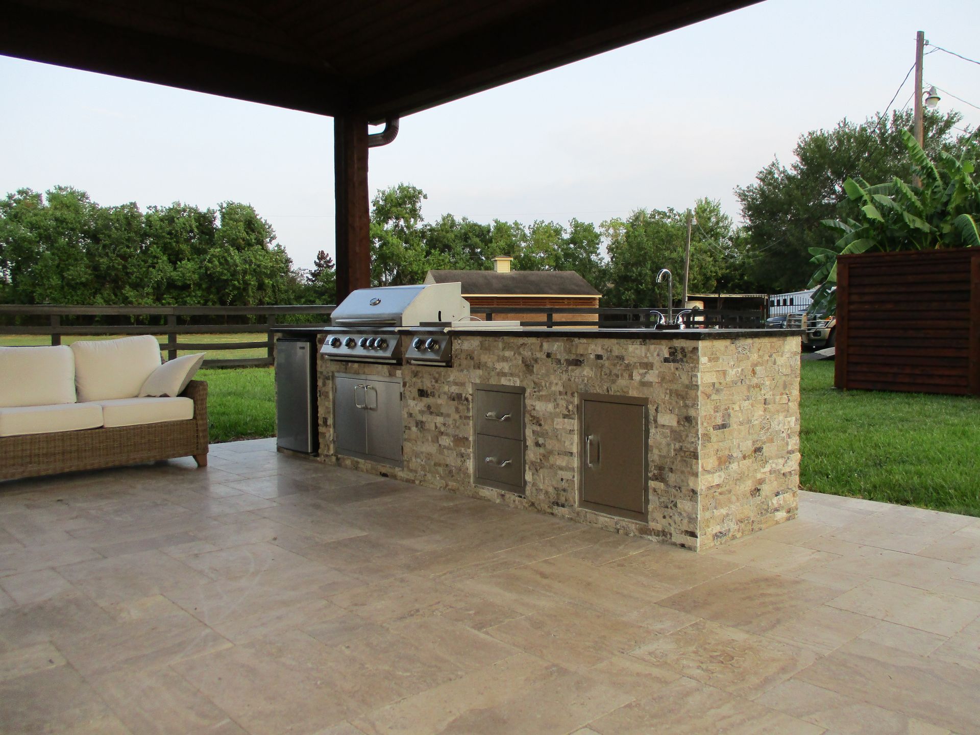 A patio with a grill and a couch under a canopy
