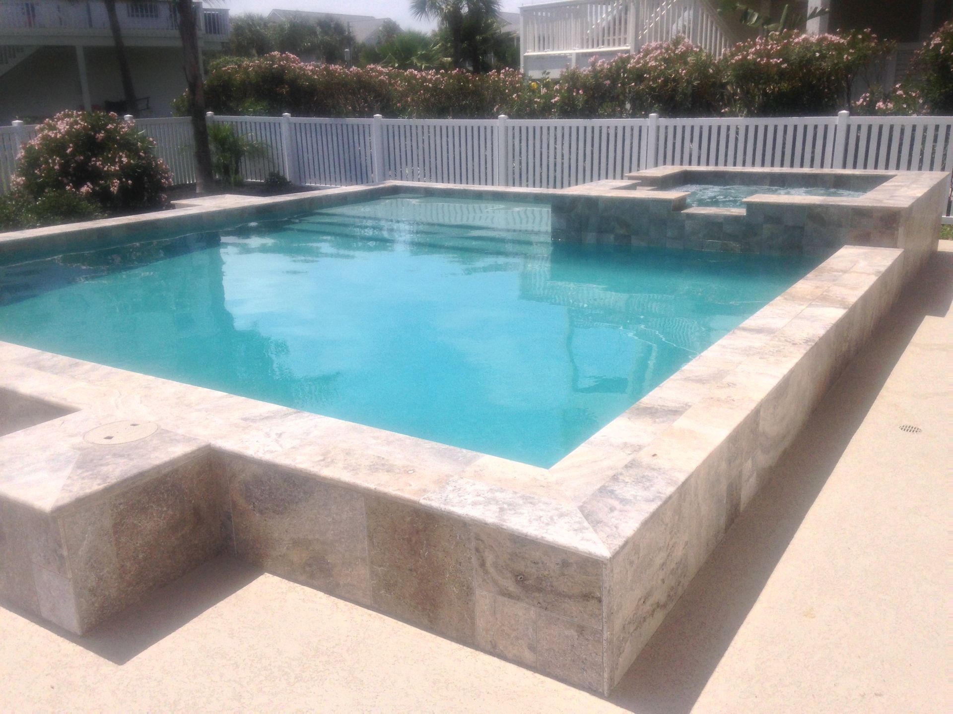 A large swimming pool with a white fence surrounding it