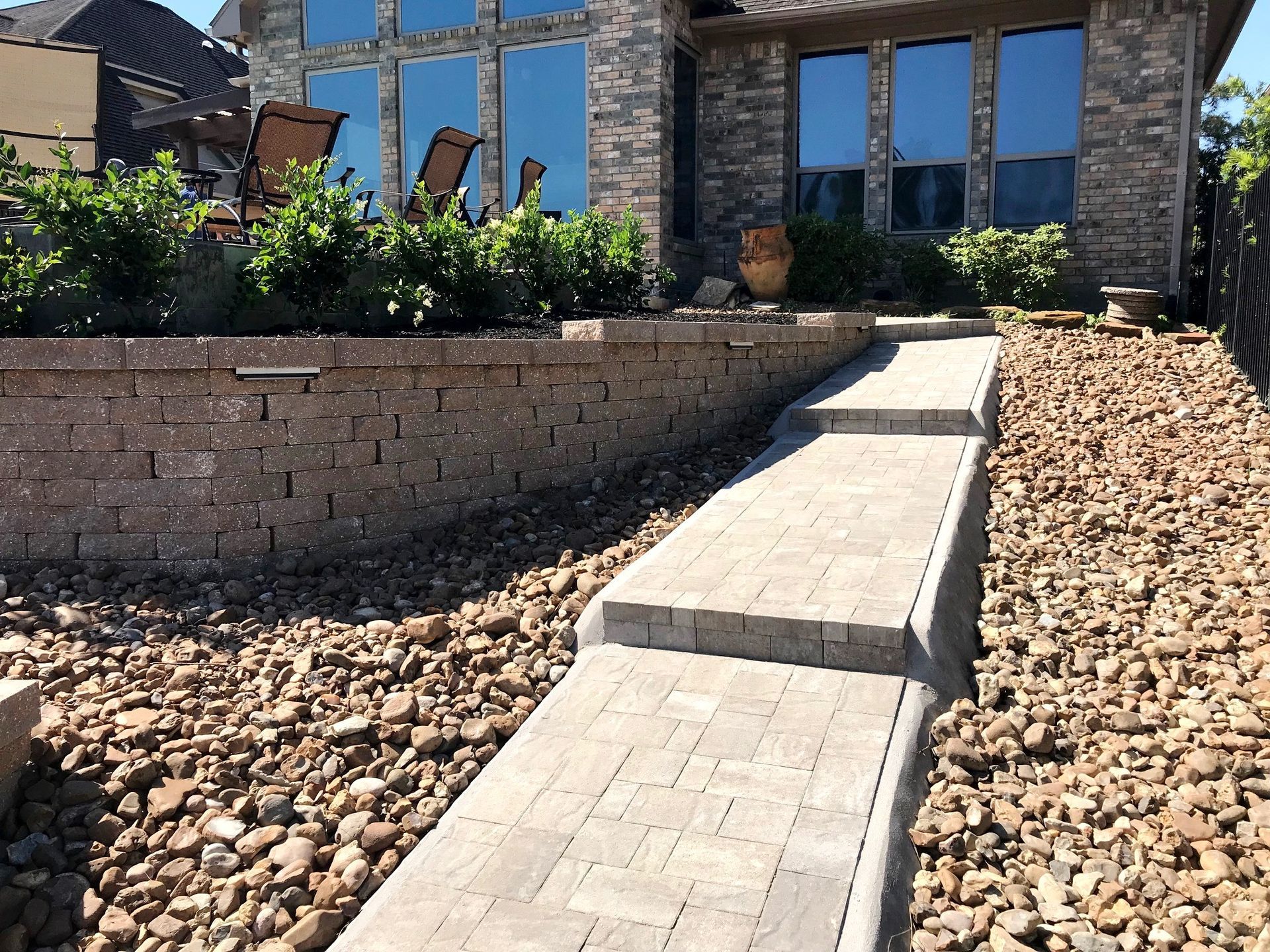 A stone walkway leading to a house with a brick wall.
