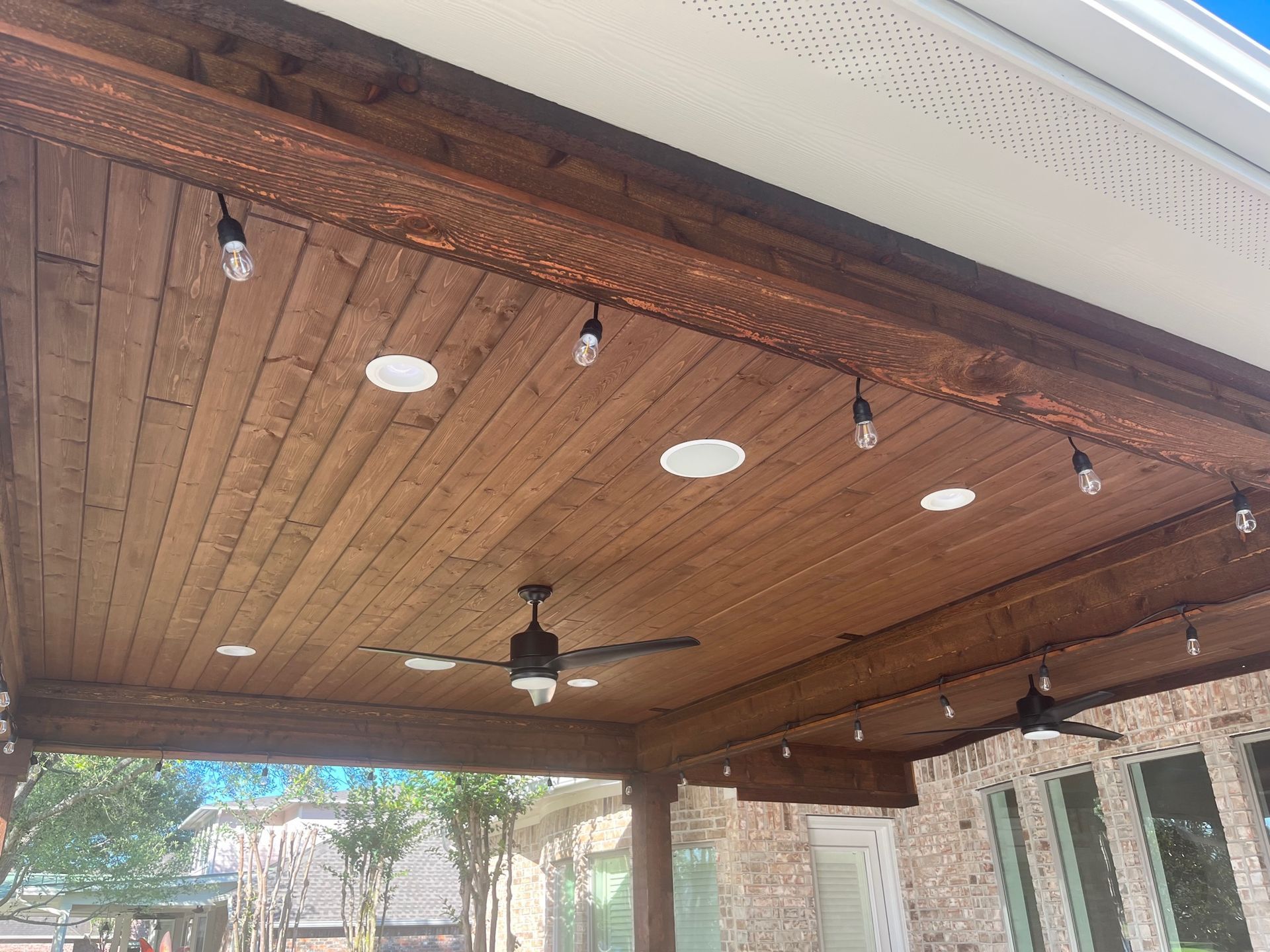 A wooden ceiling with a ceiling fan and lights hanging from it.