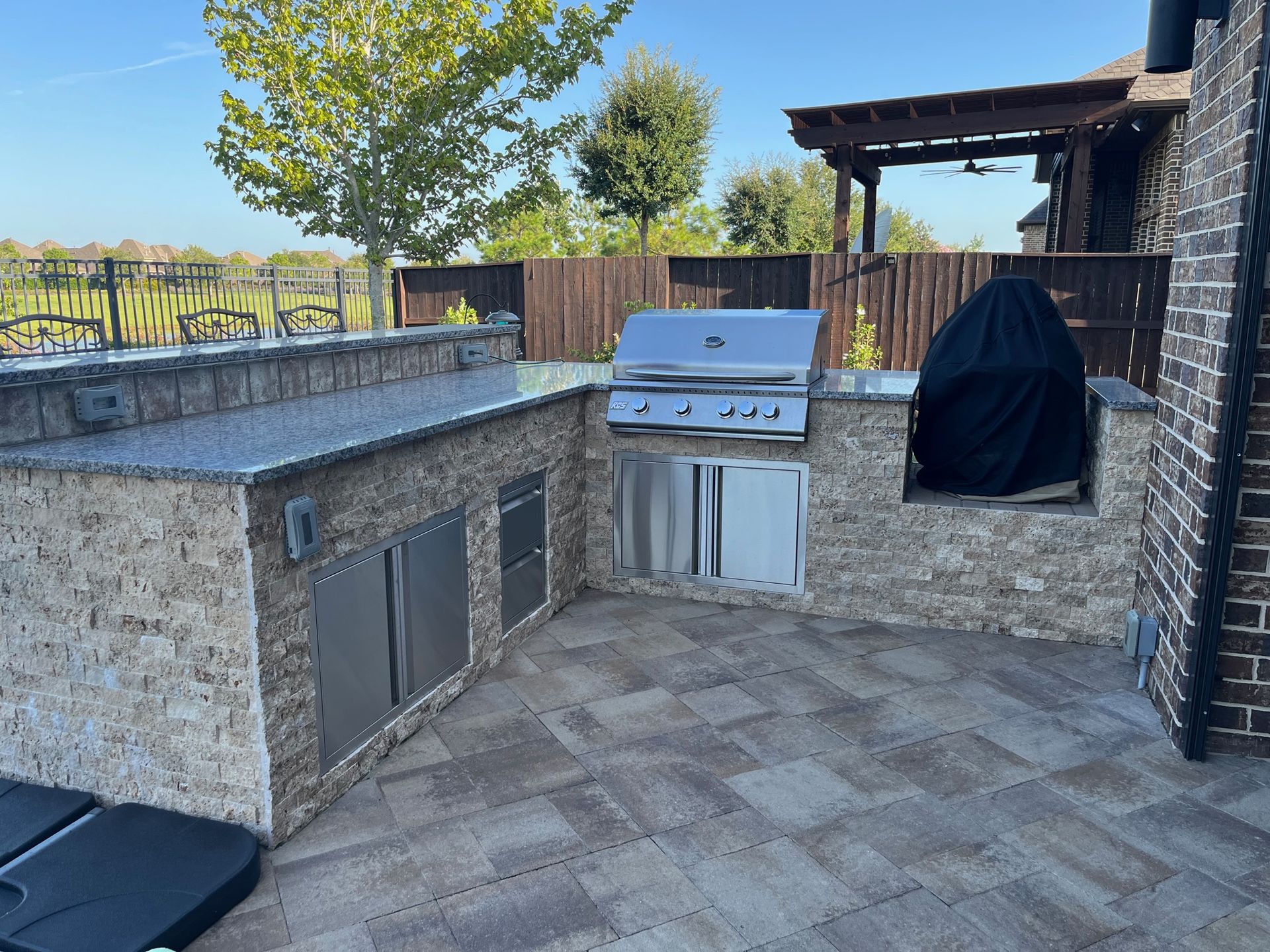 An outdoor kitchen with a grill and a brick wall