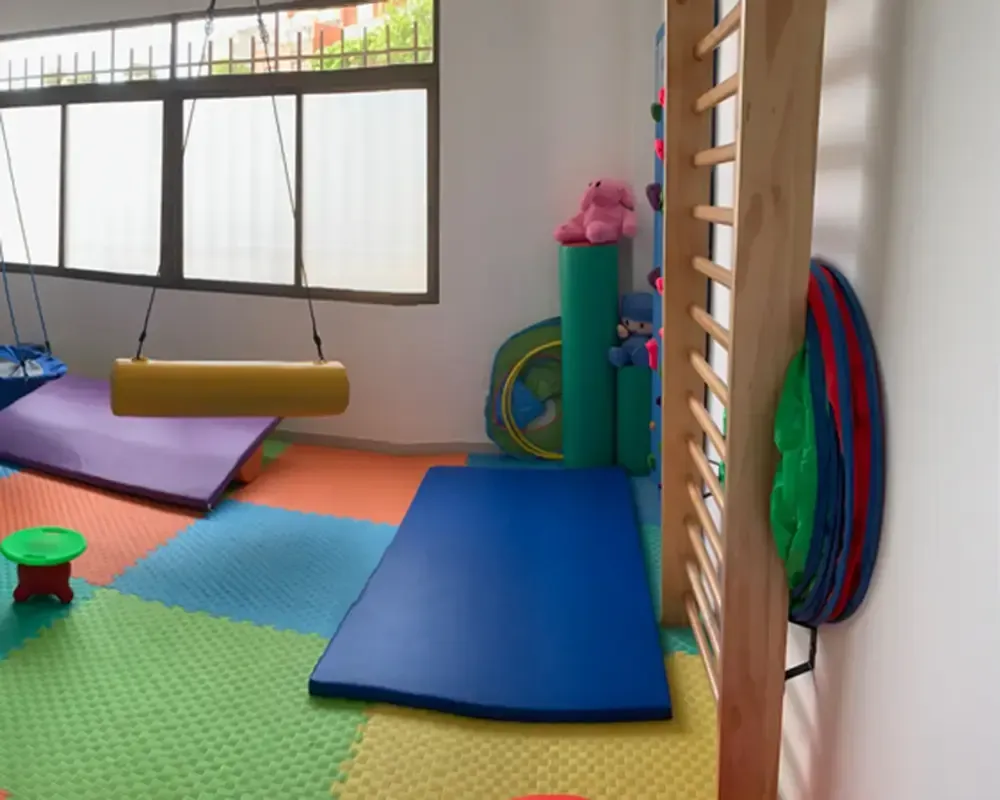 Una habitación con un columpio y una colchoneta azul.