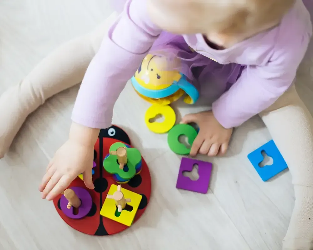 Un bebé está jugando con un rompecabezas de mariquita en el suelo.