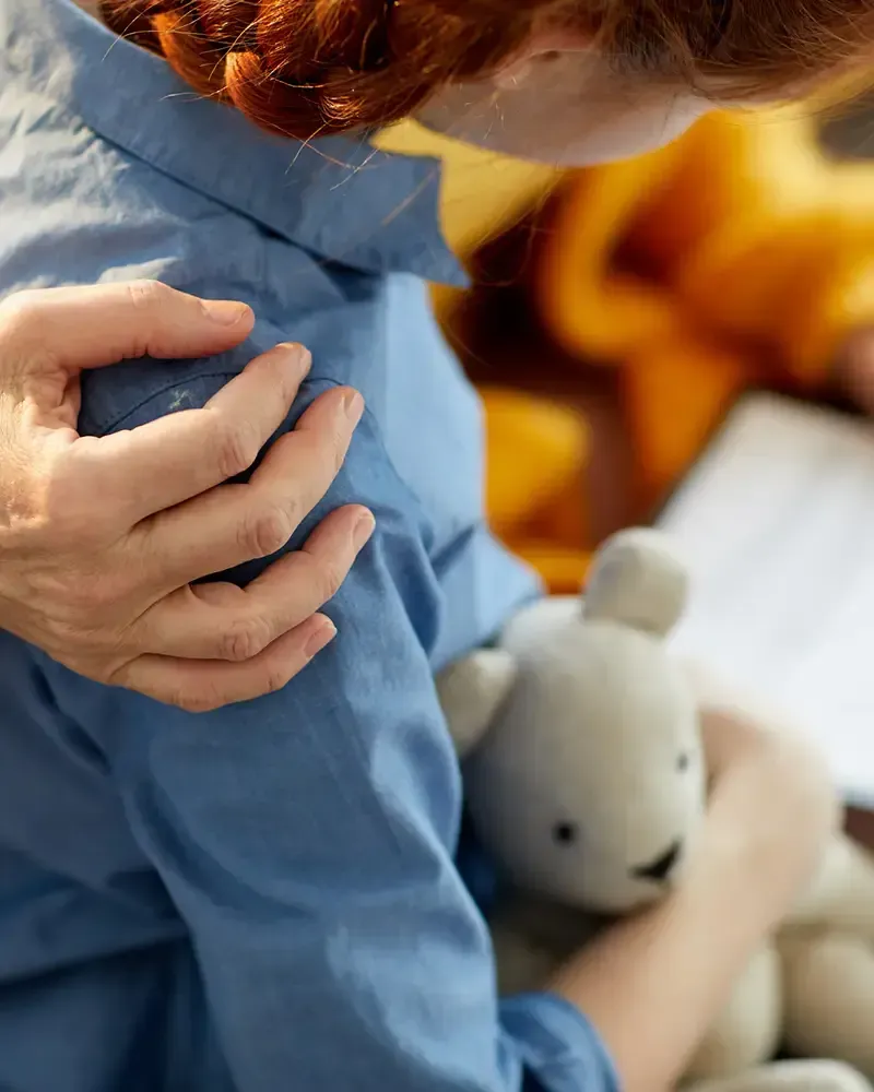Una mujer sostiene un osito de peluche y lo abraza.