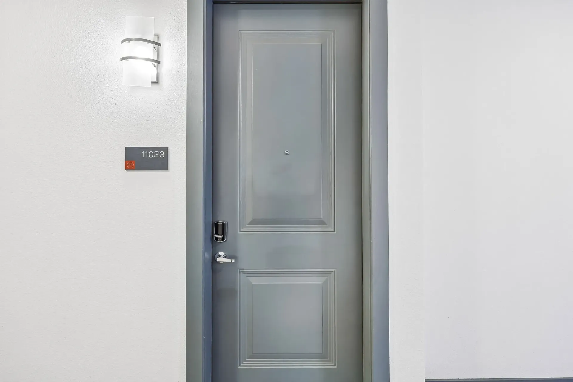 Apartment door with number 11023 and a wall sconce.