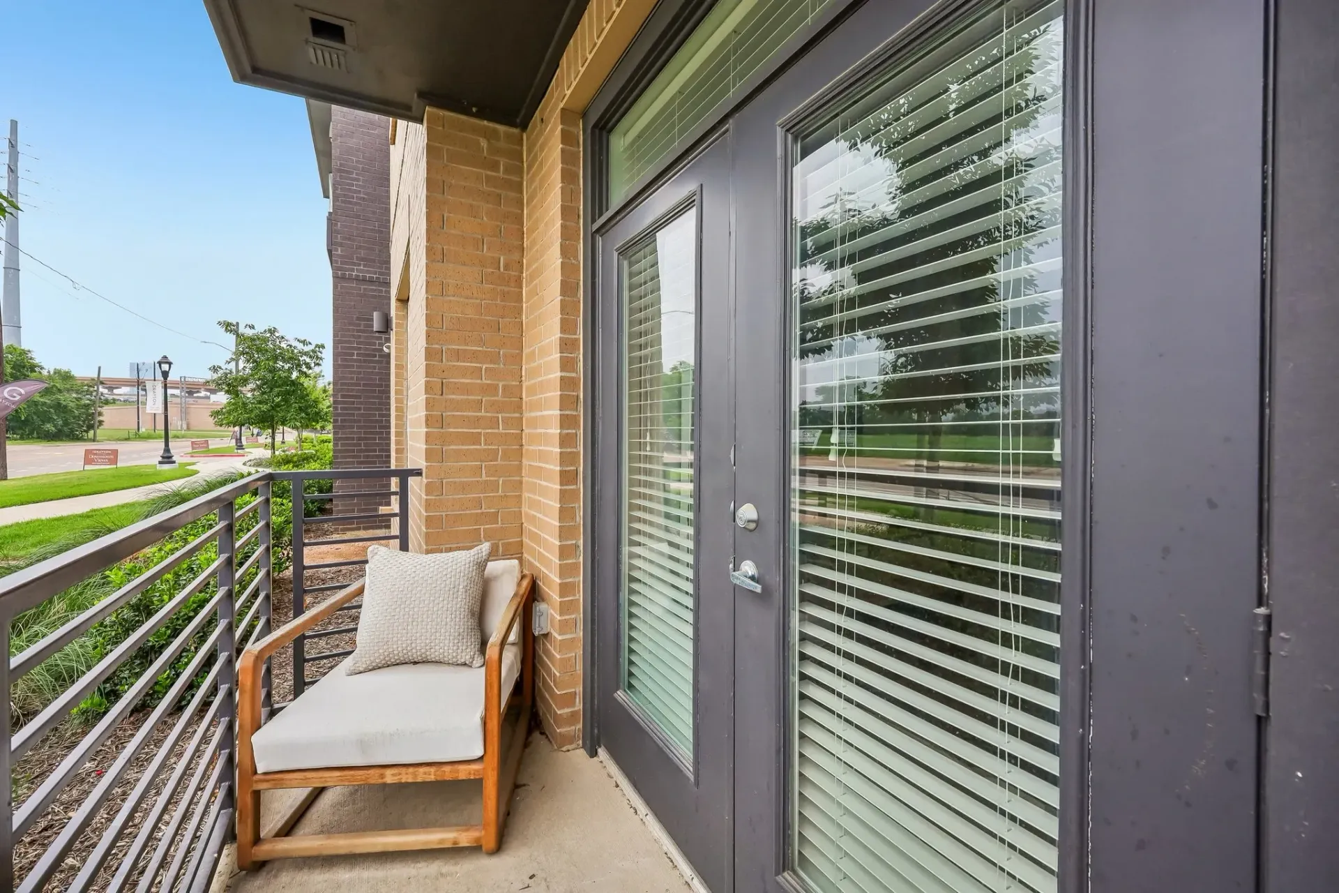 Balcony with lounge chair and view of street and building exterior.
