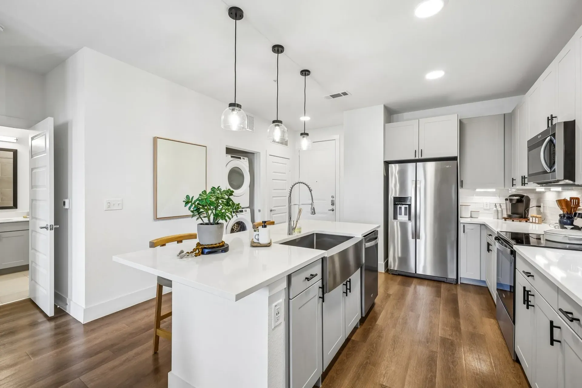 Modern kitchen with stainless steel appliances, island, and farmhouse sink.