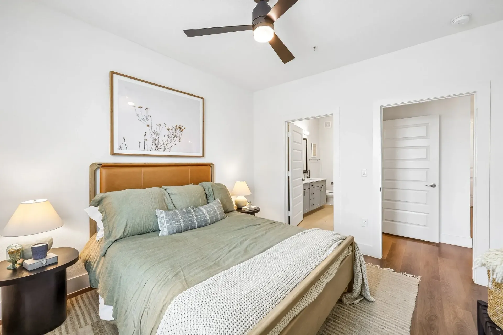 Bedroom with a king-size bed, ceiling fan, and artwork on the wall.