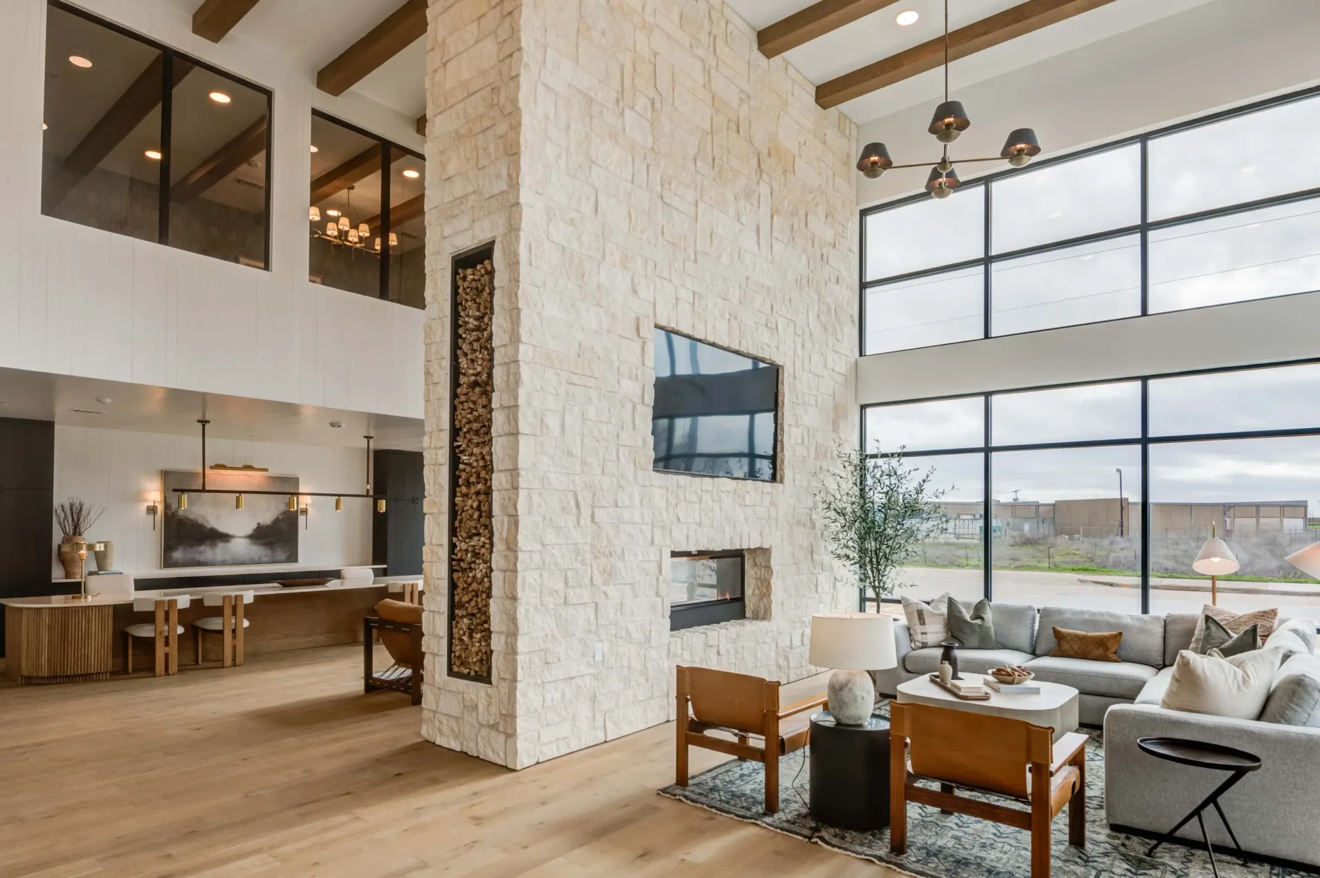 Spacious modern lounge area with a stone fireplace, large windows, and comfortable seating.