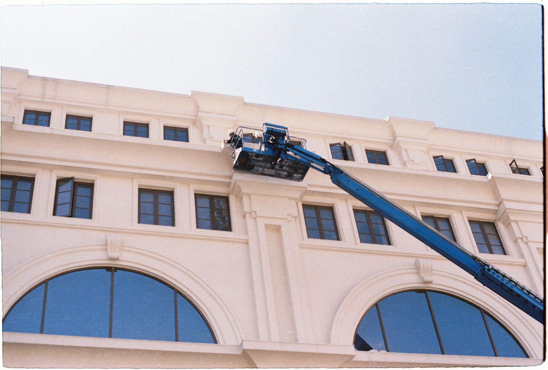 Firefighter on an extended ladder outside a beige building, reaching upper windows