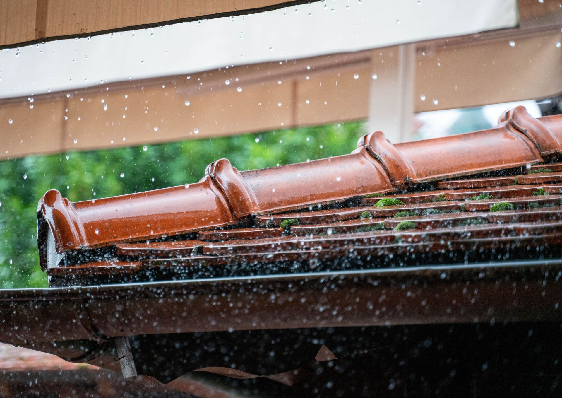 Rain falling on a terracotta-tiled roof under a wooden eave.