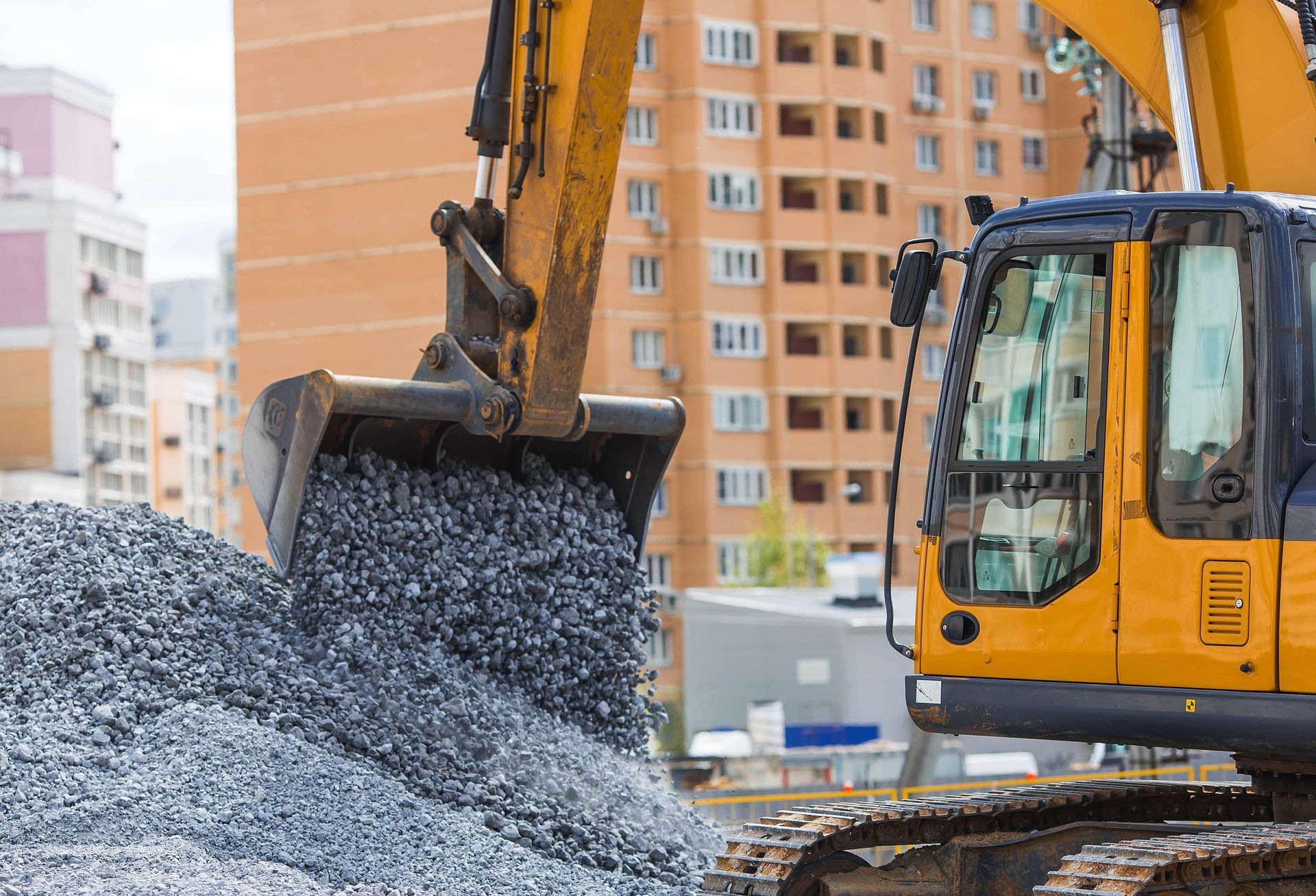 Excavator working on underground pipes. Brown dirt surrounds the black pipes, while the machine is yellow.