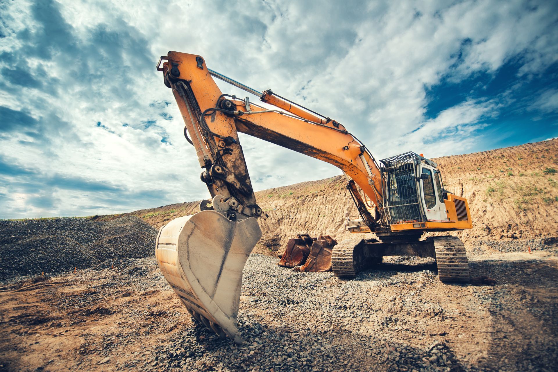 Construction site with blue and grey pipes in a trench, workers, and heavy machinery.
