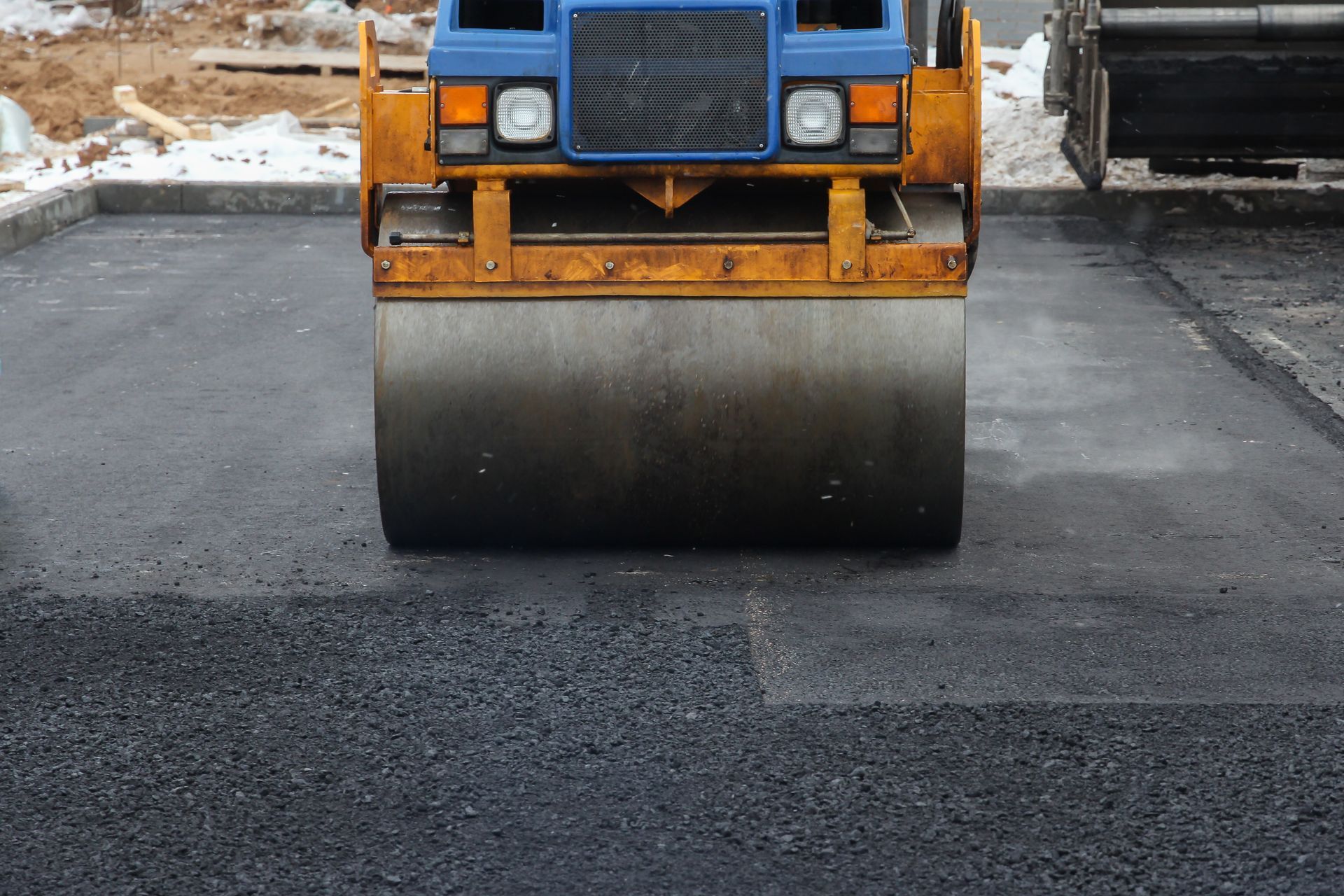 Road roller compacting fresh asphalt on a parking lot. Road roller compacting fresh asphalt on a parking lot.