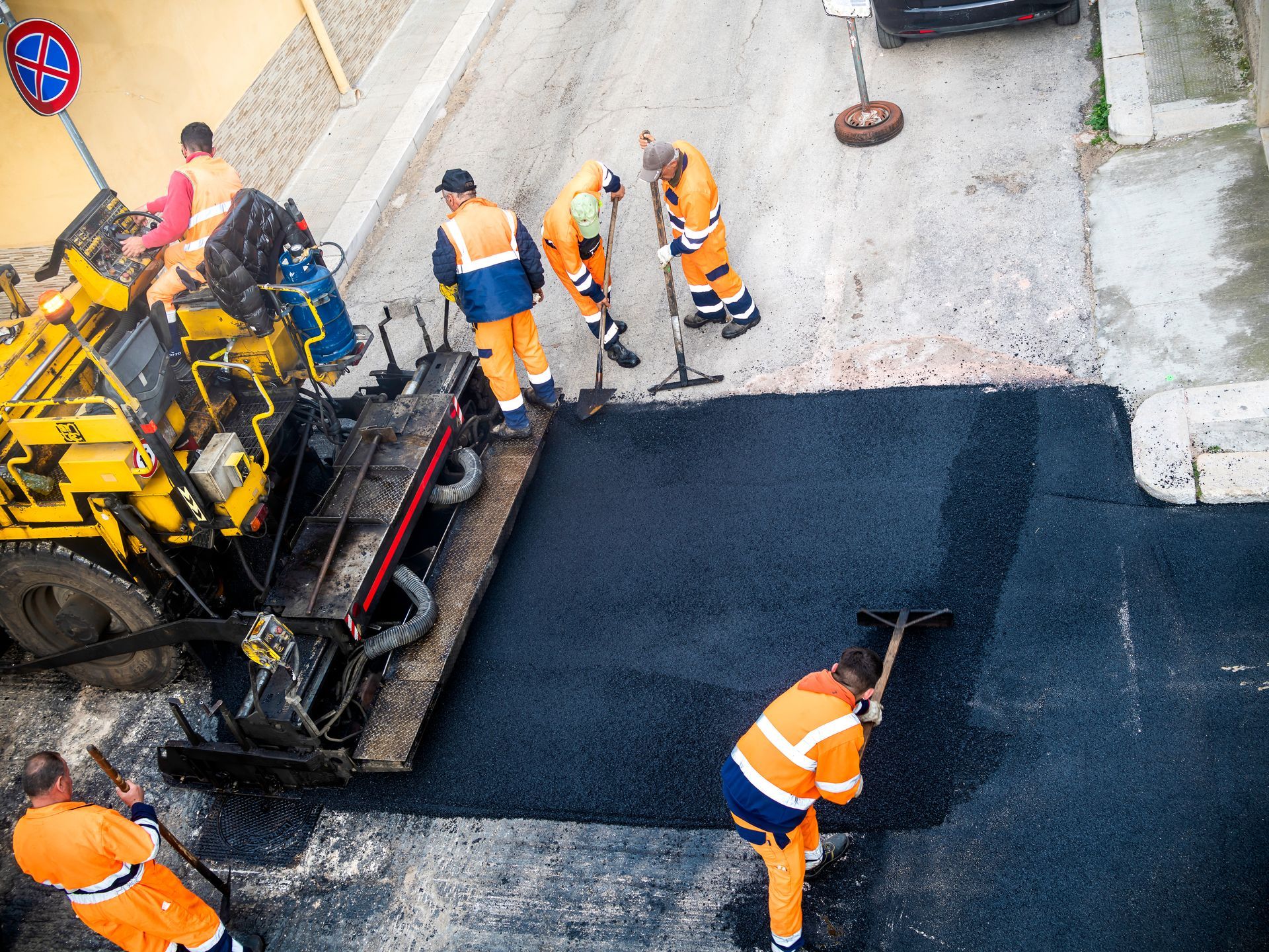 Road roller compacting asphalt on a newly paved road; blue sky in the background. Road roller compacting asphalt on a newly paved road; blue sky in the background.