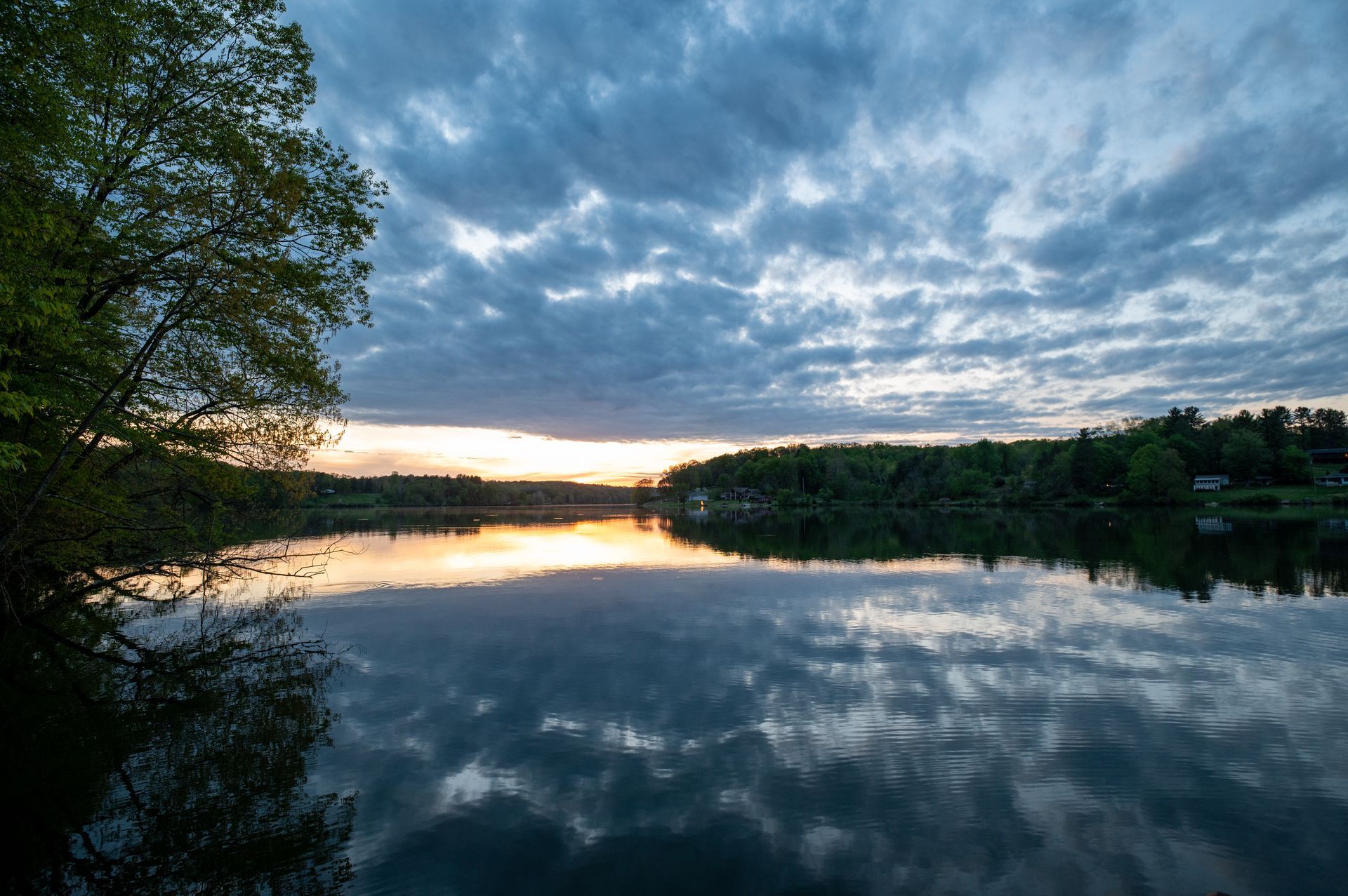 a lake with a sunset in the background and trees in the foreground .