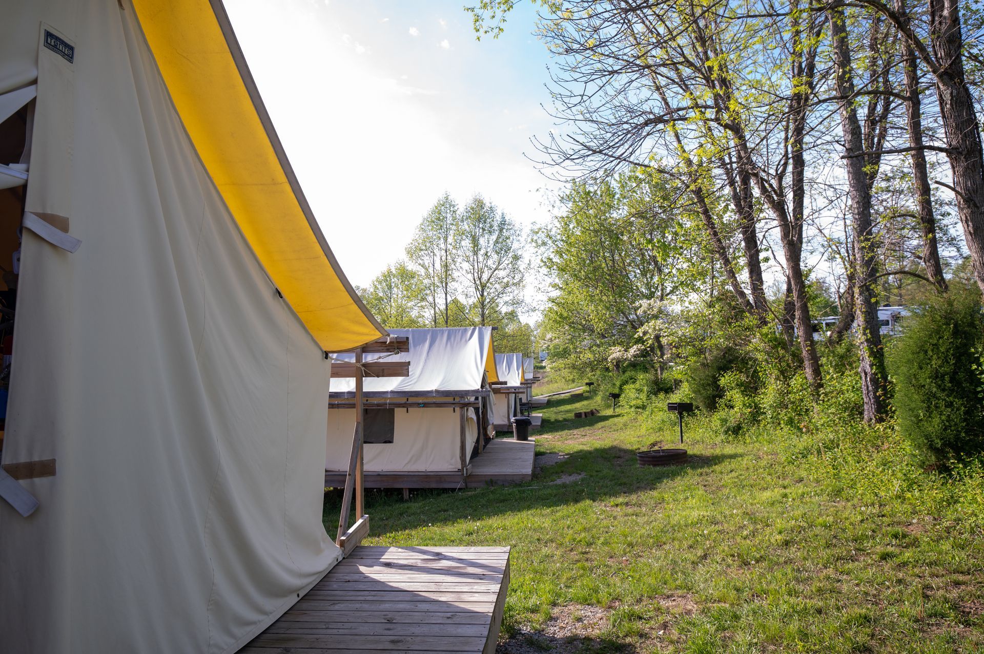 A tent with a yellow awning is sitting in the middle of a field.