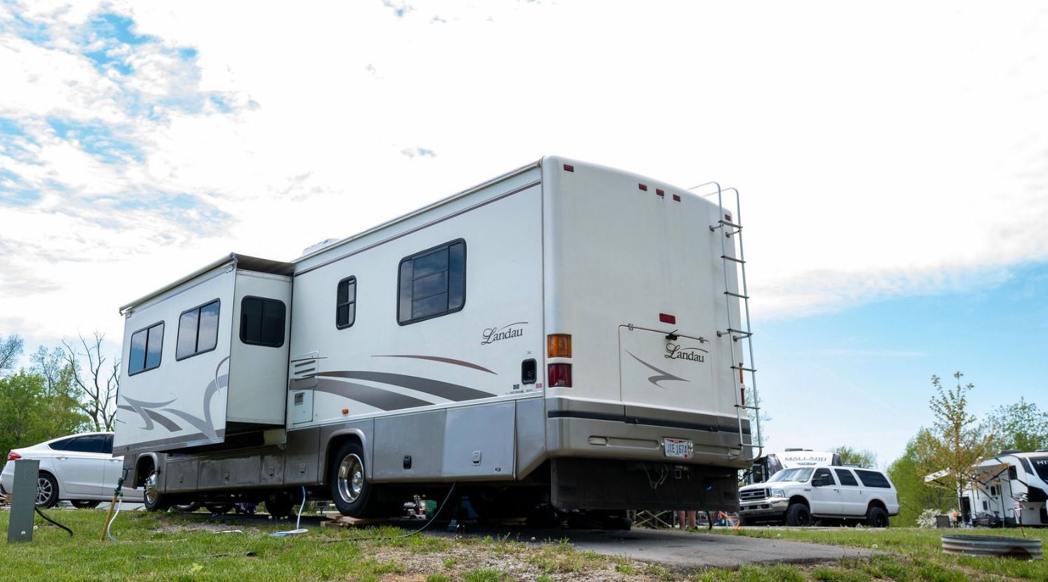 a white rv is parked in a grassy field .