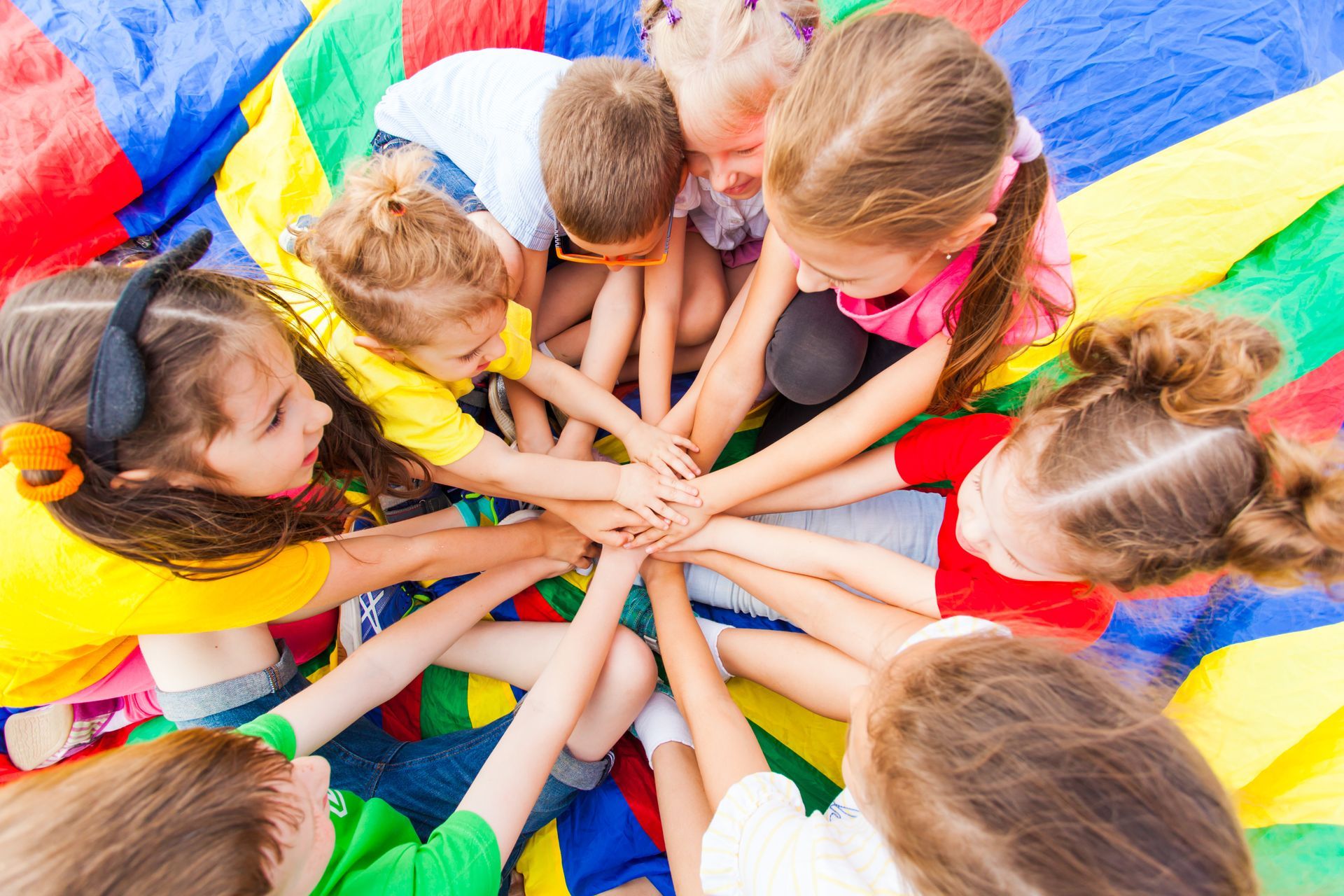 A group of children are putting their hands together in a circle.