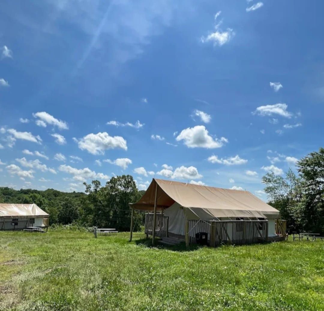 a glamping tent is sitting in the middle of a grassy field