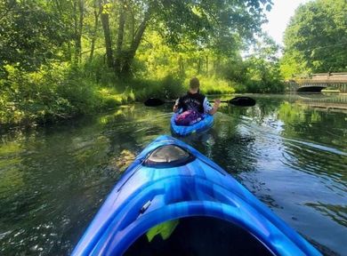 a man in a blue kayak is paddling down a river .