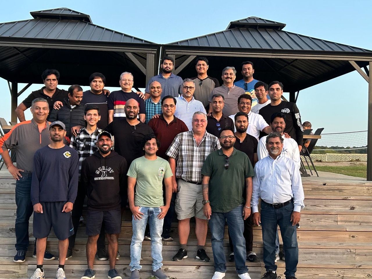 A group of men are posing for a picture in front of a gazebo.