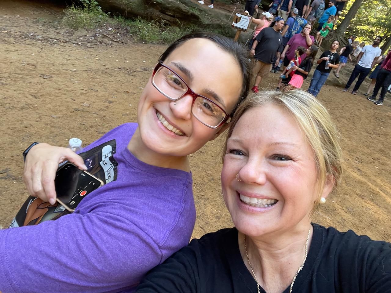 Two women are posing for a picture together in the woods.