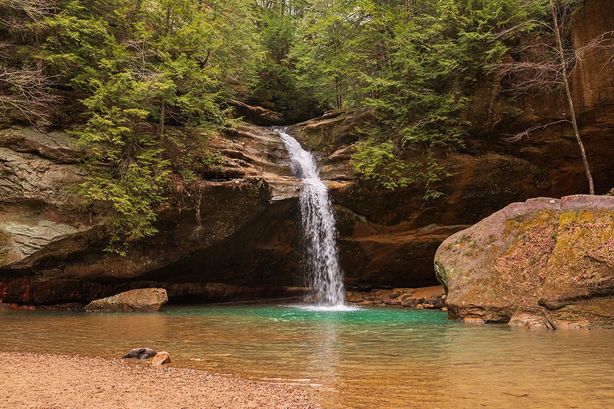 a waterfall is surrounded by trees and rocks in the middle of a forest .