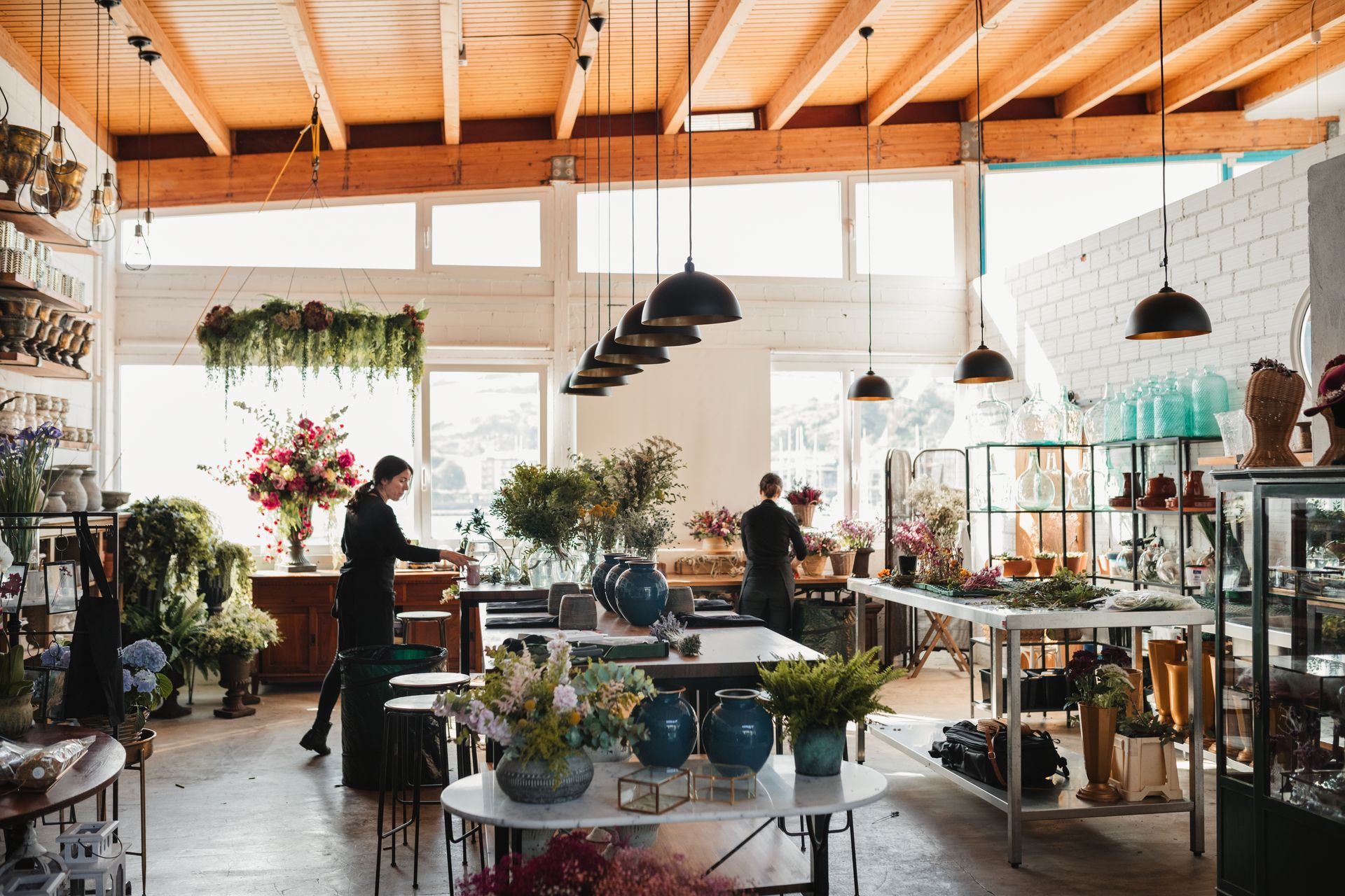 Interior plant design services showroom with staff arranging flowers and plants in modern space. Interior plant design services showroom with staff arranging flowers and plants in modern space.