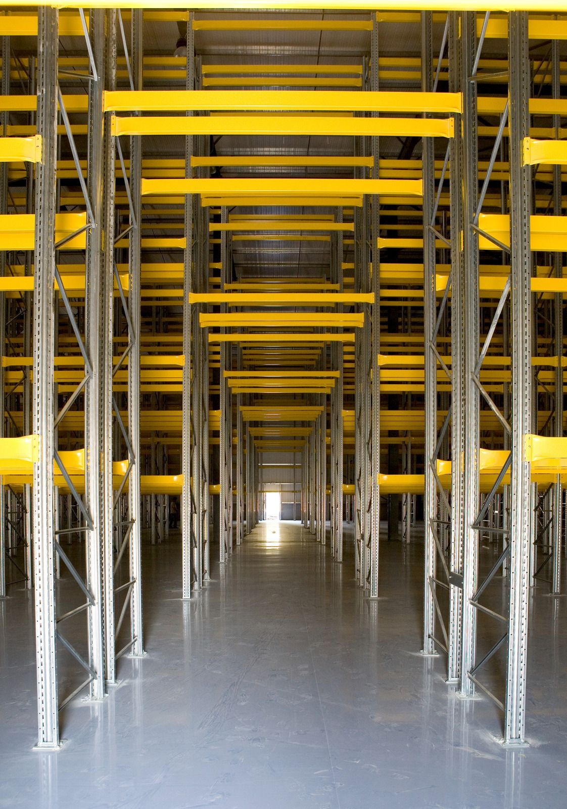 An empty warehouse with yellow shelves and a light coming through the door.