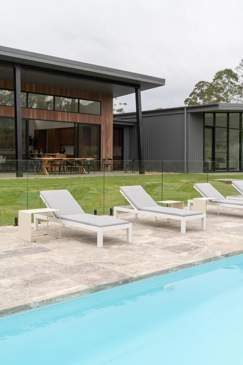 A Row Of Lounge Chairs Are Sitting Next To A Swimming Pool In Front Of A House — That Painter Guy In South Nowra, NSW
