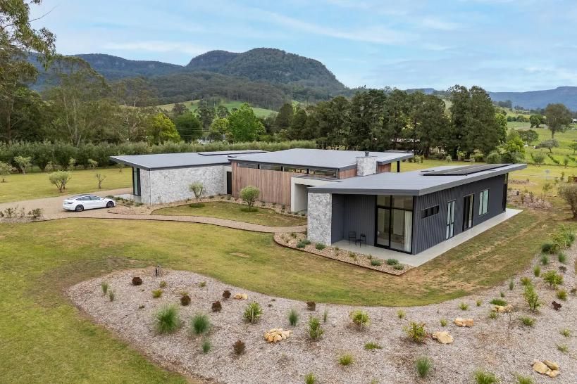 An Aerial View Of A Modern House In The Middle Of A Grassy Field With Mountains In The Background — That Painter Guy In South Nowra, NSW