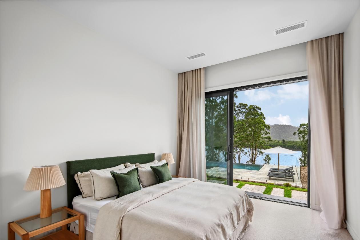 A Bedroom With A Large Bed and A Sliding Glass Door Leading To A Pool — That Painter Guy In South Nowra, NSW