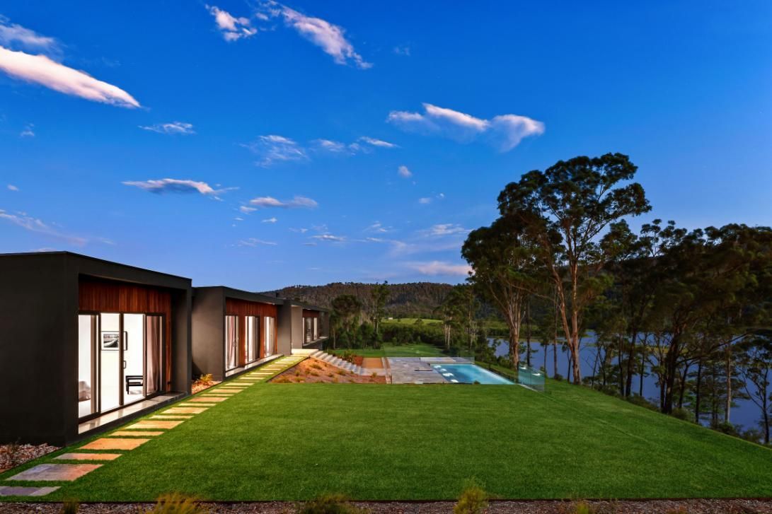 House Is Sitting On Top Of A Grassy Hill Next To A Body Of Water — That Painter Guy In South Nowra, NSW