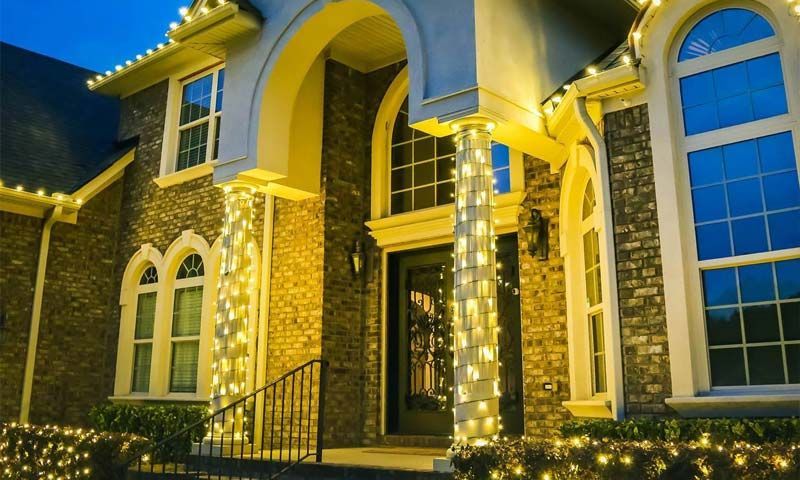 Brick house entrance lit with warm yellow lights at night, with arched windows and columns