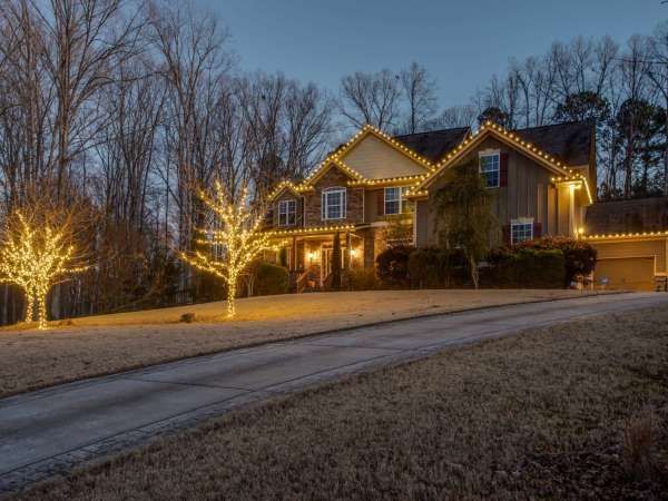 Snowy suburban house lit with warm holiday lights at dusk