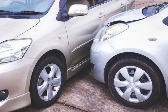Due auto beige parcheggiate molto vicine, i paraurti quasi a toccarsi in un parcheggio