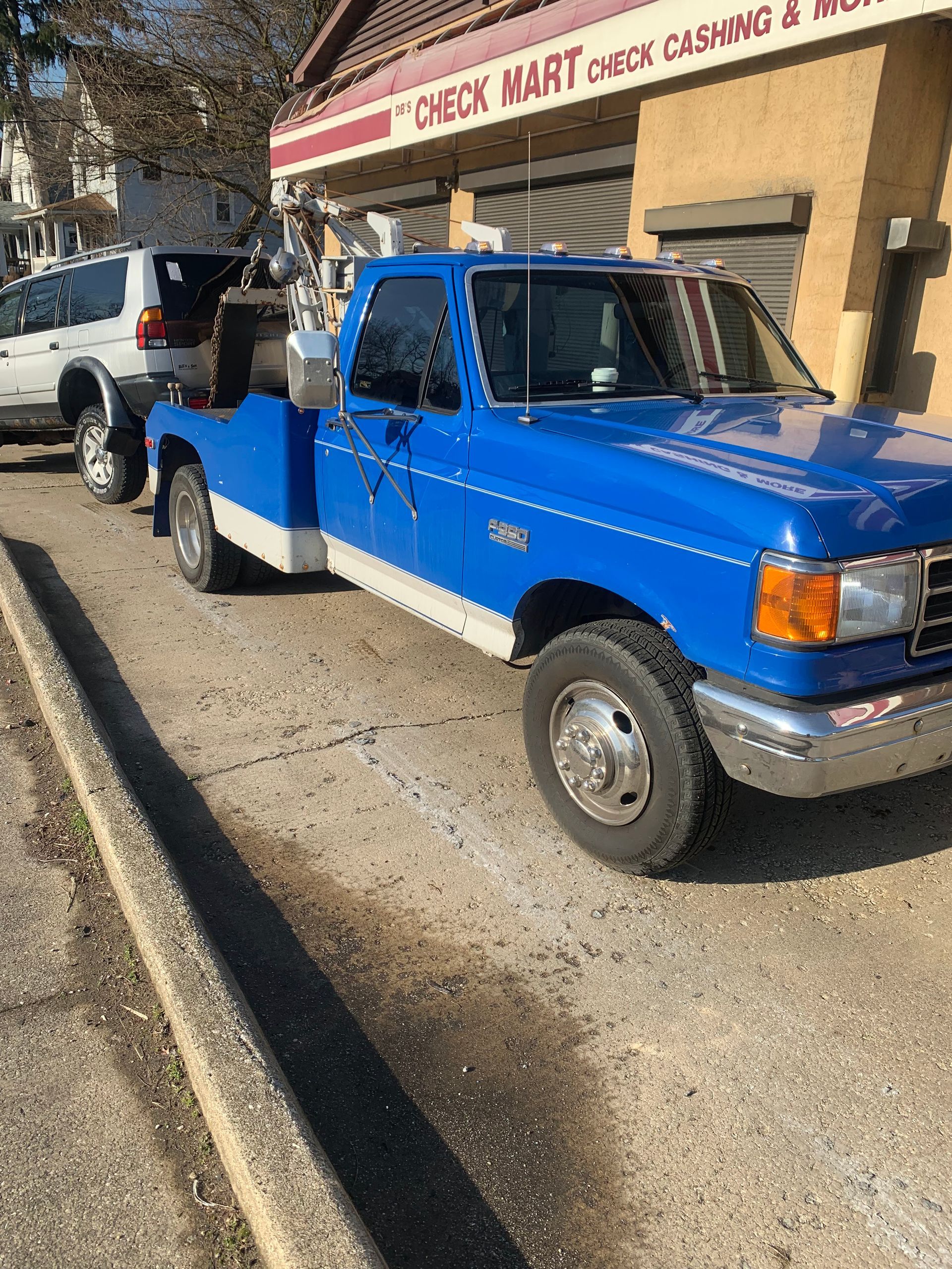Blue pickup truck parked outside a convenience store with a white SUV behind it.