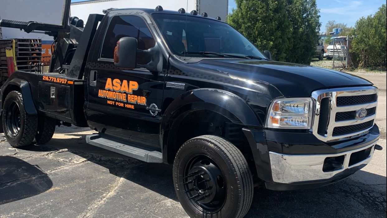 Black tow truck with ASAP lettering parked outdoors in daylight
