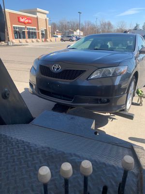 Black Toyota sedan parked in a lot near a storefront on a sunny day
