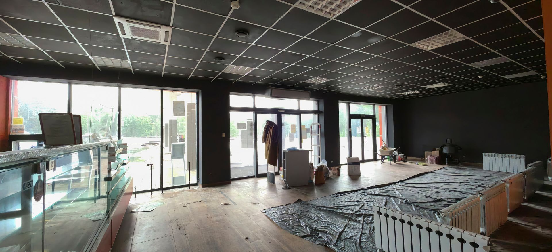 Leeres, modernes Restaurantinterieur mit schwarzer Decke, großen Fenstern und Tischen